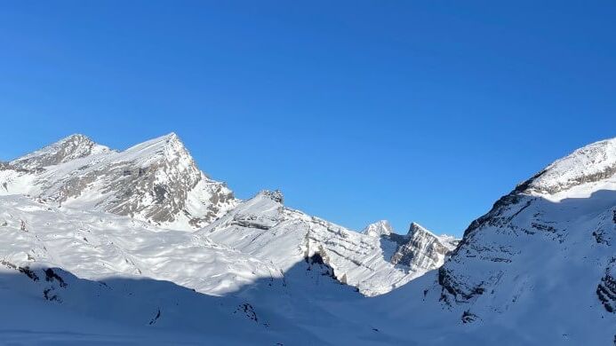 Weite Schneehänge und markante Felsgipfel der Gemmi unter klarem blauem Himmel.