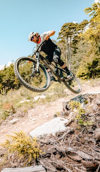 Mountainbiker im Sprung auf einem Biketrail im Wald