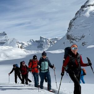 Schneeschuhgruppe vor verschneiten Felswänden im Gemmigebiet