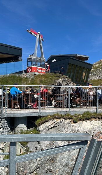 Gut besetzte Terrasse an der Bergstation, Treffpunkt für Gruppenausflüge, dahinter die Kabine der Gemmibahn