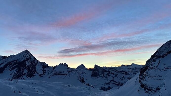 Verschneite Gipfel und Felswände der Gemmi unter einem rosa-blauen Abendhimmel.
